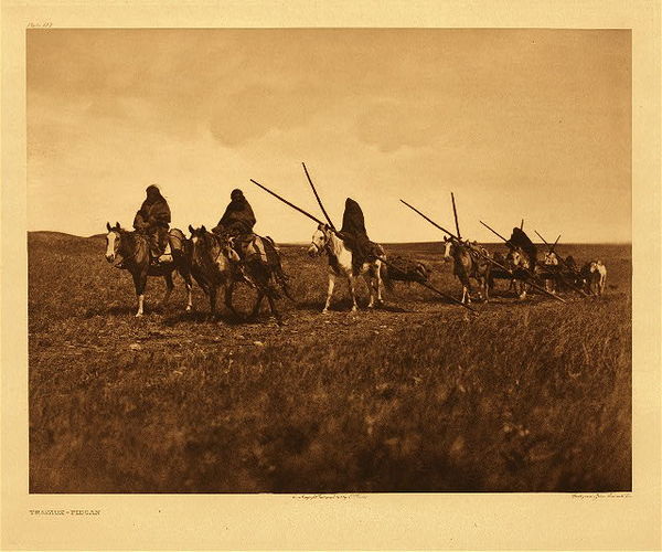Edward S. Curtis - Plate 193 Travaux - Piegan - Vintage Photogravure - Portfolio, 18 x 22 inches - Edward Curtis' Description: With the most of the plains tribes the travois was the universal vehicle for transporting camp equipment, but is now rarely seen. In the days before the acquisition of horses a smaller form of the same device was drawn by dogs. The occasion of this picture was the bringing of the sacred tongues to the medicine-lodge ceremony. <br> <br>Medicine culture in Native tribes is fascinating. Anyone seeking aid of medicine man would first fill a pipe, take it reverently to his lodge, and lay it on the ground in front of the scaffold. The healer’s acceptance of the case was indicated by smoking the pipe.