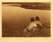 Edward S. Curtis -   Plate 197 An Idle Hour-Piegan - Vintage Photogravure - Portfolio, 18 x 22 inches - In this serene moment, two native girls sit and look out upon a still lake. The two girl’s backs are towards the camera so that the viewer can participate in the moment. Both are wearing beautiful garments and have beautiful hair, one can see how shiny it is in the detail of the photogravure. 
<br>
<br>"In disposition the Piegan are particularly tractable and likable. One can scarcely find a tribe so satisfactory to work among. In the old days of primitive customs and laws, they were fond of formalities, especially in their social relations, and these exactions were, of course, largely a part of their religion. A noteworthy phase of such form in their daily and hourly life was the excessive use of the pipe." written by Edward S. Curtis