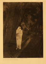 Edward S. Curtis -   Plate 218  Waiting in the Forest-Cheyenne - Vintage Photogravure - Portfolio, 22 x 18 inches - A mysterious image of a Cheyenne standing fully draped in the forest. Though often thought to be female, the subject is in fact a male. The men would wait for their girlfriends dressed this way in the forest. 
<br>
<br>Description by Edward Curtis: At dusk in the neighborhood of the large encampments young men, closely wrapped in non-comittal blankets or white cotton sheets, may be seen gliding about the tipis or standing motionless in the shadow of the trees, each one alert for the opportunity to steal a meeting with his sweetheart.