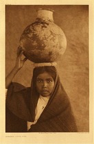 Edward S. Curtis - Plate 054  Qahatika Water Girl - Vintage Photogravure - Portfolio, 22 x 18 inches - Edward Curtis did not write a description for this photograph depicting a young Qahatika girl. She is carrying an earthen vessel on her head containing water and is dressed in a typical brown robe. The picture was taken in 1907.  
<br>
<br>Curtis Grew up in Poverty and his formal education ended in 6th grade. There is a chance that he related to the Native Americans in a way and this is why he thought it so important to photograph them. Whatever his motives were we are fortunate to have these images of a race that may have been totally lost otherwise.