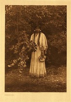 Edward S. Curtis - Plate 246 Nespilim Girl - Vintage Photogravure - Portfolio, 22 x 18 inches - A very beautiful young Nespilim girl is standing in front of the forest. She is holding a branch with many leaves and looking down as if saddened. She is holding a small beaded bag and wearing a long white deerskin dress. Her hair is in two braids as is common of her people and other tribes East of the Rocky Mountains.
<br>
<br>Caption by Edward Curtis: In the early years of the nineteenth century various explorers noted that the bands dwelling along the upper course of the Columbia, among which the Nespilim were included, wore practically no clothing. Excepting as the cold made some protection necessary. The hair of the women was arranged in two knots at the sides of the face? A method of hairdressing still in vogue among the Salish on Fraser River. Prior to the middle of the century the use of deerskin garments had become common, and gradually other customs such as the style of hairdressing here illustrated, were borrowed from the tribes east of the Rocky mountains