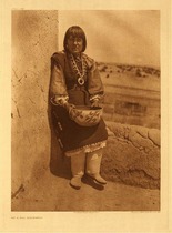 Edward S. Curtis - Plate 559 On a Sia Housetop - Vintage Photogravure - Portfolio, 22 x 18 inches - This elderly woman is pictured on a Sia housetop with the desert landscape in the background. The adobe walls are cracked but strong. She holds a beautifully deigned vessel upon her lap and is wearing a large squash blossom necklace. He dress is long and brown with small details making it a beautiful piece. Her hair is cut into a stylish “bob” with bangs. This was photographed by Edward Curtis in 1925.
<br>
<br>" The Keres Indians, a distinct linguistic stock, are found in seven pueblos, five of which are on the Rio Grande and its affluent Rio Jemez, and two nearly a hundred miles southwestward. The eastern group are Cochiti, Santo Domingo, and san Felipe on the Rio Grande, and Santa Ana and Sia on Rio Jemez. The western pueblos are Acoma and Laguna." - Edward Curtis
