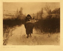 Edward S. Curtis - Plate 126 Going to Camp - Apsaroke - Vintage Photogravure - Portfolio, 18 x 22 inches - Description by Edward Curtis: This picture was made at a small winter camp on Pryor creek in the Pryor Mountains, Montana.
<br>
<br>Heading away from the camera a small woman carries a large burden. She is likely carrying a large piece of firewood on her back to keep warm in the snowy conditions. The carrying and collecting of firewood was the women’s task in Apsaroke tribes.
<br>
<br>"In stature and in vigor the Apsaroke, or Crows, excelled all other tribes of the Rocky Mountain region, and were surpassed by none in bravery and in devotion to the supernatural forces that gave them strength against their enemies. Social laws, rigidly adhered to, prevented marriage of those even distantly related, and the hardships of their life as hunters eliminated infant weaklings. The rigors of this life made the women as strong as the men; and women who could carry a quarter of a buffalo apparently without great exertion, ride all day and all night with a raiding war-party, or travel afoot two hundred and fifty miles across an unmarked wilderness of mountains, plains, and swollen streams in four days and nights, were not the women to bring forth puny offspring."
