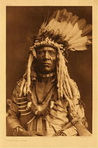 Curtis' Description: The accoutrement of this brave (Apohsuyis) comprises the well-known war-bonnet of eagle-feathers and weasel-skins, deerskin shirt, bone necklace, grizzly-bear claw necklace, and tomahawk-pipe of Hudson's Bay Company origin.