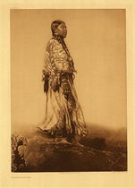 Edward S. Curtis - *50% OFF OPPORTUNITY* Plate 280 Wishham Woman - Vintage Photogravure - Portfolio, 22 x 18 inches - In this beautiful portrait of a Wishham woman Edward Curtis captures every detail of her attire. Looking out to the right the subject is dressed in a full length gown and has long braids. The background is blurred, either by Curtis’ artistic doing or by fog in the distance.
<br>
<br>"Fish, especially salmon, were plentiful far beyond their needs, and were so easily taken that the people were indolent and inert, lacking the initiative, the energetic force, the manliness characteristic of tribes whose livelihood must be gained largely by hunting. In common with most of the other tribes of the north Pacific coast, they were unusually licentious that chastity was practically unknown; and to a remarkable degree they lacked the tribal instinct, so that killing by hired assassins and by supposed magical means became a recognized practice of frequent occurrence." - Edward S Curtis