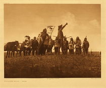 Edward S. Curtis - Plate 182 The Scouts Report - Atsina - Vintage Photogravure - Portfolio, 18 x 22 inches - The Chief of the scouts, returning to the main party, tells in the vigorous and picturesque language so natural to the Indians what he has seen and experienced. While he speaks, the war-leader stands slightly in advance of his men, and carefully listening to the words of the scout, quickly forms his plan of action. – Edward Curtis
<br>
<br>The Atsina tribe is interesting to follow, but not easy. "The Atsina, commonly designated Gros Ventres (Big Belly) of the Prairie, are of the Algonquian stock and a branch of the Arapaho. Their name for themselves is "Aaninen," Atsina being their Blackfoot name. Judging by their vague tradition, their original separation from the Arapaho must have occurred in early times; but care should be taken not to confuse this primal separation with their return to the north from an extended visit to the Arapaho during the last century."
<br>
<br>Edward Curtis, in Volume V, describes the territories where they resided as difficult to pin down, and chose to spend the first four pages creating a picture of the Atsina through the stories of their battles. This photogravure is then a snapshot of what must have occurred over and over in the history of this tribe. 
<br>
<br>In the first recited battle - Close to defeat, a single gunshot from the first and only gun possessed by the Atsina. The earliest intertribal battle known in their traditions occurred when the tribe moved back to the north and into Shoshone territory. They were greatly outnumbered and were on the verge of being defeated when the lone gun in both tribes was used to shoot one of the Shoshone. Not being familiar with a firearm they “looked upon the mysterious killing as due to some spiritual power, and fled in terror.” 
<br>
<br>The stories found in Volume V of The North American Indian go on to describe the superiority they gained by acquiring horses, the losses they suffered when over-powered in winter and the decimation as they retreated in starvation.