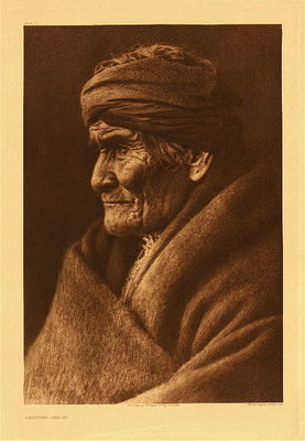 Edward S. Curtis -   Plate 002 Geronimo - Apache - Vintage Photogravure - Portfolio, 22 x 18 inches - “This portrait of the historical old Apache was made in March, 1905. According to Geronimo's calculation he was at the time seventy-six years of age, thus making the year of his birth 1829. The picture was taken at Carlisle, Pennsylvania, the day before the inauguration of President Roosevelt, Geronimo being one of the warriors who took part in the inaugural parade at Washington. He appreciated the honor of being one of those chosen for this occasion, and the catching of his features while the old warrior was in a retrospective mood was most fortunate.” – Edward Curtis
<br>
<br>Edward Curtis Apache images reveal the various elements of life in the warrior tribe. In the ethnographic study of the “The North American Indian” is rich in its depiction of the culture and lifestyle, with some emphasis on significant individuals.
<br>
<br>In the late 19th century, Geronimo had one of the most well-known Indian names, and is memorable today. There are a number of stories about him, some violent and some peacemaker. In the end he realized the fate of his people was set and pursued the importance of learning new ways to make it work. However, his many attempts at this were thwarted by the inconsistency of the Federal government. 
<br>
<br>Toward the end, as a very independent persona, Geronimo became associated with resisting settling in the reservation, escaping three times with a band of renegades. As a result, he was captured and spent the rest of his life as a prisoner of war.
<br>
<br>“General Crook said to me, ‘Why did you leave the reservation?’ I said: ‘You told me that I might live in the reservation the same as white people lived. One year I raised a crop of corn, and gathered and stored it, and the next year I put in a crop of oats, and when the crop was almost ready to harvest, you told your soldiers to put me in prison, and if I resisted, to kill me. If I had been let alone, I would now have been in good circumstances, but instead of that you and the Mexicans are hunting me with soldiers."   -  Geronimo
<br>
<br>The following statement is telling regarding his spiritual perspective, which leaves room for both attempts at working toward a solution and defensive action.
<br>
<br>"When a child my mother taught me the legends of our people; taught me of the sun and sky, the moon and stars, the clouds and storms. She also taught me to kneel and pray to Usen for strength, health, wisdom, and protection. We never prayed against any person, but if we had aught against any individual, we ourselves took vengeance. We were taught that Usen does not care for the petty quarrels of men." ~ Geronimo