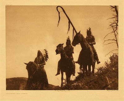 Edward S. Curtis - Plate 147 Apsaroke War Group - Vintage Photogravure - Portfolio, 18 x 22 inches - This image taken by photographer Edward S. Curtis displays warriors of either the Lumpwood or Fox societies. Lumpwood and Fox are both tribal military organizations which inspired native men to be fierce and brave in battle. Each society had four staffs, which had symbolic uses in war, two straight staffs and two that were bent at the end.
<br>
<br>Each spring new staffs were produced and given to brave members. Those who were given a staff then were responsible for making a lone stand against the enemy in battle. They would plan the staff into the ground in a place which the warrior would not retreat past. It was known that the staff holder may have to die if necessary. After a season of warfare had passed, if the staff bearer was still alive he would then take the staff as a trophy.
<br>
<br>The curved staffs would be wound with narrow strips of deerskin an outer covering of strips of otter skin, with tails hanging down. The straight staffs bore a tuft of eagle feathers at its top. Interestingly, it was not considered a disgrace to refuse the staff, for it was known that it was not something to take lightly and if a man felt that he was not ready to die he could decline without ruining his reputation.
<br>
<br>In this photograph by Edward S. Curtis the warrior on the right holds a curved staff and would be the bearer of the great responsibility described above. The photo was taken in 1905. This incredibly fine image is available for sale in our Aspen Art Gallery.