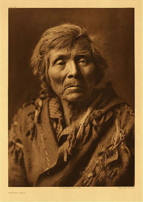 Edward S. Curtis - *50% OFF OPPORTUNITY* Plate 241 Spokan Man - Vintage Photogravure - Portfolio, 22 x 18 inches - The Spokan were a peaceful people and this humble image of a Spokan man embodies that peaceful feeling. Staring right into the camera this man could easily be mistaken for a woman with his long braided hair. In very simple attire and well-lit to see the contours of his face.
<br>
<br>"Only once did the Spokan engage in hostilities with the United States. After the conclusion of the Stevens treaties with the Yakima, Nez Perce, and others in 1855 the Spokan regarded with apprehension the nearer approach of the multiplying white man; for Governor Stevens informed them that he would make a treaty with them also. His plan was thwarted by the uprising of the dissatisfied Yakima, Wallawalla, and Cayuse, as well as numerous coast tribes, and no treaty was ever made with the Spokan."  From Edward Curtis' "North American Indian", Volume II