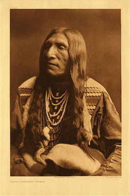 Edward S. Curtis - *50% OFF OPPORTUNITY* Plate 191 Double Runner - Piegan - Vintage Photogravure - Portfolio, 22 x 18 inches - Description by Edward Curtis: Double Runner's is an excellent type of the Piegan physiognomy, as well as the ideal North American Indian as pictured by the average person. The native name of this individual is Ahjutomahka.
<br>
<br>Piegan Men and women wore the typical deerskin clothing worn by most plains Indians with ornamentation made from porcupine-quills and with beads, made from silver-berry seeds. This man has long beautiful wavy hair and is dressed in patterned clothing. Adorned with jewelry he looks like an important man. 
<br>
<br>"The Piegan, the Bloods, and the Blackfeet are closely related and allied Algonquian tribes, and have usually been designated collectively as Blackfeet."