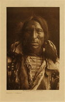 Edward S. Curtis -   Elk Boy - Ogalala - Vintage Photogravure - Volume, 12.5 x 9.5 inches - Born 1848. At fourteen he accompanied a party under the great leader White Swan against the Apsaroke. At twenty he lead his first war-party, which met and killed thirty Apsaroke, Elk Boy himself counting two first coups in the fight. One of the Apsaroke, who were surrounded on a rocky hill, dashed out alone; Elk Boy rushed to meet him, shot him down, struck him with his gun, and scalped him. Another coming to the assistance of the Apsaroke was shot by others of the Sioux, and Elk Boy struck him as he fell. He was engaged in eleven battles against the Apsaroke, Shoshoni, Pawnee, Assiniboin, Arikara, and Ponca; fought once against the soldiers.
<br>
<br>Provenance: Original Subscription Set #59. George D. Barron, Rye, NY