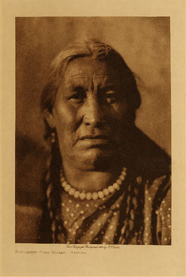 Edward S. Curtis - *50% OFF OPPORTUNITY* Scattered Corn Woman - Mandan - Vintage Photogravure - Volume, 12.5 x 9.5 inches - "Corn was the chief staple of the Mandan, and was grown in considerable quantities. The fields consisted of small patches of rich alluvial land cleared of trees and shrubbery; the ground was worked with a wooden dibble, and with a hoe bladed with a buffalo-scapula. Each family's garden was divided into three to seven beds of six rows each, the rows a step apart and the hills in the row the same distance."