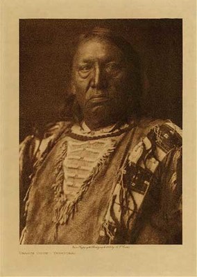 Edward S. Curtis - *50% OFF OPPORTUNITY* Charge Crow - Yanktonai - Vintage Photogravure - Volume, 12.5 x 9.5 inches - Born near Standing Rock in 1850. When in his seventeenth year he joined a war party against the Apsaroke near the Little Bighorn, the Yanktonai capturing a number of horses. While fighting the Flatheads, Charge Crow killed one and took his horse. He led a war-party on foot, and encountering the Atsina near Fort Belknap, Montana, captured fifty horses. Having found an old police badge, he visited a camp of Cree and told them he was an officer. They believed him, and Charge Crow stole most of the horses in the camp, and got away with them safely. Although he fasted often and prayed to the sun, he never had a vision; he attributes his success in war to the potency of his prayers. He married at twenty-one.
<br>
<br>The Yanktonai are known to have resided in North Dakota and Montana until reservation days and the total population in Curtis time was around 6,500.
<br>
<br>Charge Crow frowns into the camera in this image, he is dressed traditionally. This photogravure was taken in 1908 by Edward S. Curtis and is now available at our Aspen Art Gallery.
<br>
<br>Provenance: 
<br>Art Institute of Chicago, Ryerson & Burnham Library