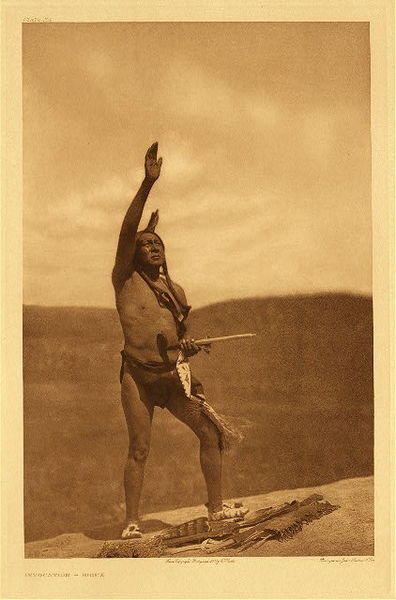 Edward S. Curtis - Plate 109 Invocation - Sioux - Vintage Photogravure - Portfolio, 18 x 22 inches - “Scattered throughout the Indian country are found spots that are virtually shrines. These are often boulders or other rocks which through some chance have been invested with mythic significance, and to them priest and war-leaders repair to invoke the aid of the supernatural powers. The half-buried boulder on which the suppliant stands is accredited with the power of revealing to the warrior the foreordained result of his projected raid. Its surface bears what the Indians call the imprint of human feet, and it is owing to this peculiarity that it became a shrine. About it the soil is almost completely worn away by the generations of suppliants who have journeyed hither for divine revelation” – Edward Curtis <br> <br>A medicine-man is called wichasha-waka, “man of mystery”. His power is derived from spirits that appear in visions, which he may have in his own tipi as he sleeps at night, or out upon a hill whither he has gone for the express purpose of becoming a medicine man, or in the observance of the Vision Cry. <br> <br>There were five principal religious rites; Sun Dance is the most important ceremony practiced by the Lakota (Sioux) and nearly all Plains Indians. It was a time of renewal for the tribe, people and earth. Vision Cry implores The Mystery for a vision. “Ghost Keeper," "Buffalo Chant" (puberty), and "Foster-parent Chant."