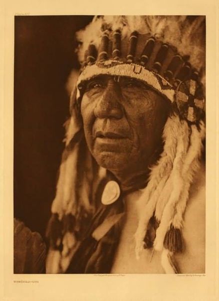 Edward S. Curtis - Plate 677 Wakonda - Oto - Vintage Photogravure - Portfolio, 18 x 22 inches - In this striking portrait Curtis captures a close-up of an Oto male in traditional garb. This image is one of only 36 large portfolio plates from Volume XIX, focusing on the Indians of Oklahoma, the Wichita, Southern Cheyenne, Oto, Southern Comanche, and the Peyote Cult.