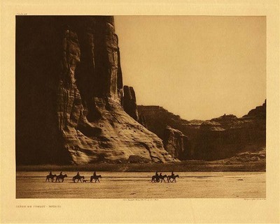 Edward S. Curtis -   Plate 028 Canon de Chelly - Navaho - Vintage Photogravure - Portfolio, 18 x 22 inches - Written by Edward Curtis: A wonderfully scenic spot is this in northeastern Arizona, in the heart of the Navaho country - one of their strongholds, in fact. Cañon de Chelly exhibits evidences of having been occupied by a considerable number of people in former times, as in every niche at every side are seen the cliff-perched ruins of former villages.<br><br>QUOTES FROM "THE NORTH AMERICAN INDIAN: "The Navaho are a pastoral, semi nomadic people whose activities center in their flocks and small farms...While the Navaho leads a wandering life, the zone of his movements is surprisingly limited; indeed the average Navaho's personal knowledge of his country is confined to a radius of not more than fifty miles."<br><br>DWELLINGS: A Navaho house is called a "Hogan" and is made of logs, brush, and earth. Summer houses are also utilized and made of brush with a windbreak.<br><br>"Although raiders and plunderers since known to history, the Navaho cannot be designated a warring tribe, for however courageous they may be, their lack of political integrity has been an obstacle to military organization. They never have had a tribal chief, properly so called, while many leading men could never command more than a small following."