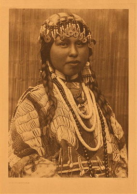 Edward S. Curtis -   Plate 281 Wishham Bride - Vintage Photogravure - Portfolio, 22 x 18 inches - Wishham tribes were located in Oregon and Washington and the traditional dress was generally made of skins, breech cloth, or woven blankets. In this Edward Curtis photo however the beautiful Native subject is dressed for a wedding ceremony. She is very elaborately dressed in beaded clothing and jewelry. The marriage arrangements for the Wishham tribes would involve a messenger sent from the groom’s family to the bride’s father. The messenger would negotiate with him for a set price a very businesslike affair.<br><br>On the day of the wedding the price would be payed and gifts would also be offered for other relatives of the bride. They would feast for days alternating between houses as part of the celebration. Polygamy was not frowned upon, but one would have had to be quite wealthy to support more than one wife. The most affluent of the tribe may have up to 8 wives. Adultery was punished according to Edward S. Curtis’ North American Indian.