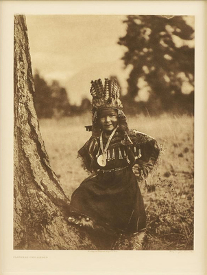 Edward S. Curtis -   Plate 235 Flathead Childhood - Vintage Photogravure - Portfolio, 22 x 18 inches - This image was published in Volume VII of "The North American Indian" by Edward S. Curtis. Volume VII recorded Salishan and Tribes of the Interior: Collvilles, Kalispel, Lakes, Methow, Nespilim and Sanpoel, Sinkiuse, Spokan, Coeur D'Alenes, Flatheads, and Pend D'Oreilles. These tribal regions consisted of Washington, Idaho, and Montana- The country lying between the Rocky Mountains and the Cascades, and south of the Canadian border to the forty seventh parallel (forty-sixth in Montana).<br><br>This portrait depicts a young Flathead child fully dressed in traditional garb smiling in the outdoors.