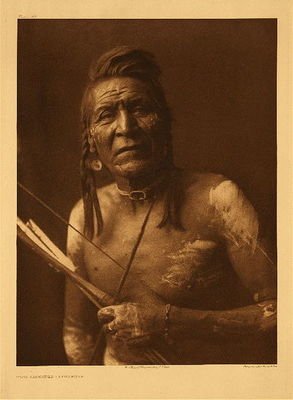 Edward S. Curtis -   Plate 113 Two Leggings - Apsaroke - Vintage Photogravure - Portfolio, 22 x 18 inches - Born about 1848. River Crow; Not Mixed clan; Lumpwood organization. Having no great medicine derived from his own vision, he was adopted into the Tobacco order by Bull Goes Hunting, who gave him his medicine of a fossil, or a stone, roughly shaped like a horse facing two ways. Two Leggings thus became a war-leader. In pursuing some Piegan who had killed a woman in the Apsaroke camp opposite Fort C.F. Smith on the Bighorn, he counted "dakshe" and captured a gun by the same act-a high honor. Led two parties against the Hunkpapa Sioux, each time taking scalps. Captured fifty horses from the Yanktonai at Fort Peck, and with Deaf Bull led a party that brought back eighty horses from the Teton Sioux.