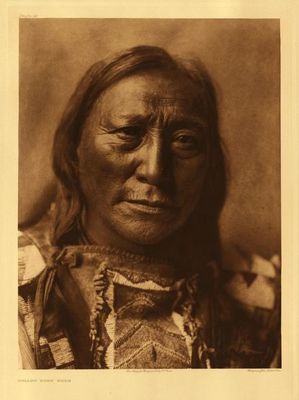 Edward S. Curtis -   Plate 082 Hollow Horn Bear - Vintage Photogravure - Portfolio, 22 x 18 inches - The life of this Brule Sioux is briefly treated in Volume III, page 186.<br><br>Born 1850. First war-party at twelve against Pawnee. At nineteen he took the pipe and led a party, which killed a number of Pawnee wood-haulers. Struck a first coup-"kill right"-in that battle. After that his father, Iron Shell, desired him to take that name, but he said that he would take his grandfather's name instead, and make the name Hollow Horn Bear good. During his career as a warrior, he counted coup many times and participated in twenty-three fights with Pawnee, Omaha, Ponca, Ute, Arikara, and United States troops. He was present at the Custer fight.<br><br>*Additional biographical notes (not written by Curtis): <br>*A son of the famous, mid-19th century Brule chief Iron Shell, he nearly died as an infant during the first U.S. Army attack on a Lakota village, at the Blue Water battle near Fort Laramie in 1855. After the attack, his mother recovered the infant from the wreckage of the village. Hollow Horn Bear became a distinguished leader of the Brule. His portrait graced the old, U.S. 14-cent stamp.<br><br>Hollow Horn Bear traveled often to Washington, D.C., rode in the inaugural parade of Theodore Roosevelt, and died in the Capitol in March, 1913, of pneumonia contracted while riding in the rain during the inaugural parade for Woodrow Wilson.