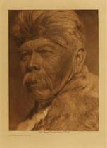 Edward S. Curtis - *40% OFF OPPORTUNITY* A Chukchansi Yokuts - Vintage Photogravure - Volume, 12.5 x 9.5 inches - Dress: men, and a great many women, more only loin cloth; other women had double aprons of shredded willow-bark, tules, or sedge, more rarely of skin. IN cold weather both sexes used robes made of strips of the skins of rabbits, coyotes, or water foul. Moccsasins were rare. Men and women drew their hair together at the back of the head and tied it in a bunch or a sheaf with a cord, or passed a head-band from the base of the cranium up over the top. In the north women generally tattooed the chin, and some men the chest and forearms; and both sexes occasionally wore a bit of bird-bone, or, rarely, a cylinder of clamshell in an orifice in the lobe of each ear and the septum of the nose. In the south, however, they did not tattoo, and ornaments were long, slender pendants of clam-shell worn about the neck, in the lobes of the ears, and the septum. - Edward Curtis