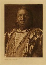 Edward S. Curtis - Charge Crow - Yanktonai - Vintage Photogravure - Volume, 12.5 x 9.5 inches - Born near Standing Rock in 1850. When in his seventeenth year he joined a war party against the Apsaroke near the Little Bighorn, the Yanktonai capturing a number of horses. While fighting the Flatheads, Charge Crow killed one and took his horse. He led a war-party on foot, and encountering the Atsina near Fort Belknap, Montana, captured fifty horses. Having found an old police badge, he visited a camp of Cree and told them he was an officer. They believed him, and Charge Crow stole most of the horses in the camp, and got away with them safely. Although he fasted often and prayed to the sun, he never had a vision; he attributes his success in war to the potency of his prayers. He married at twenty-one.<br><br>The Yanktonai are known to have resided in North Dakota and Montana until reservation days and the total population in Curtis time was around 6,500.<br><br>Charge Crow frowns into the camera in this image, he is dressed traditionally. This photogravure was taken in 1908 by Edward S. Curtis and is now available at our Aspen Art Gallery.