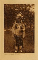 Edward S. Curtis - Door-of-Lodge Grizzly - Flathead - Vintage Photogravure - Volume, 12.5 x 9.5 inches - This photo was taken by Edward S. Curtis in 1910 of Door-of-Lodge Grizzly who associates himself with the Flathead tribe. The mother of Door-of-Lodge Grizzly (commonly called Mois) was half flathead and half Iroquois, and his father was half flathead and half Nez Perce. Pictured here in full headdress or war bonnet with a coup stick. He is dressed up in a fringed deerskin shirt, beaded moccasins, and a blanket.<br><br>Printed on Dutch Van Gelder paper this image is available for sale in our Aspen Art Gallery.