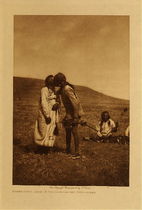Edward S. Curtis -  *40% OFF OPPORTUNITY* Atsina Crazy Dance - A Dancer Kisses the Grandfather - Vintage Photogravure - Volume, 12.5 x 9.5 inches - The Crazy Dance ceremony lasted four days and four nights with dancing lasting well into the night. During the night the crazy dancers’ wives were taken by the Grandfathers beyond the camp circle in order to receive medicines from them. On their return, each woman was kissed by every one of the dancers. Her husband then ended by kissing the Grandfather. The kissing of the Grandfather is depicted in this image by Edward S. Curtis taken in 1908. This photogravure is on display in our Aspen Art Gallery.