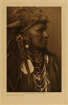 Edward S. Curtis -   White Man Runs Him (Portrait) (One of Custer’s Crow Scouts) - Vintage Photogravure - Volume, 12.5 x 9.5 inches - Born about 1854 or 1855. Mountain Crow; Big Lodge clan; Lumpwood organization. His only coup was counted by the capture of a tethered horse. Noted for his many successful horse-raiding expeditions against the Sioux. <br>Scouted with Custer in his last campaign, and was one of the party of three or four scouts who, at the dawn of the morning of the Custer fight, first sighted the Sioux camp. A small party of Crow and Arikara scouts under Lieutenant Varnum, having traveled nearly all night, arrived shortly before dawn almost a the summit of the highest peak in the Wolf mountains, where the party slept for a short time. At approaching light White Man Runs Him and a couple of companions went to the top of the high peak which gave them the first view of the Sioux encampment. Following Custer's coming up to view the valley and its camp of hostiles, he was with Custer until the Sioux made their attack on him. White Man Runs Him's recollections of that day are exceedingly clear. The author spent several days with him traveling carefully over the ground covered on the day of the disastrous fight on the Little Bighorn, part of this time being accompanied by general C.A. Woodruff. <br>White Man Runs Him possesses no medicine derived from his own vision, but once fasted four days and four nights in the Bighorn mountains on a peak known to the Apsaroke as "Where White Man Runs Him Fasted." Of his seven wives he gave up six "good ones," that is, those who had borne him children; to discard such was an indication of a strong heart.