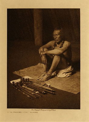 Edward S. Curtis -   In the Medicine Lodge - Arikara - Vintage Photogravure - Volume, 12.5 x 9.5 inches - The healers of disease were usually men belonging to the medicine fraternity, but such membership was not essential. In the treatment they used many herbs in connection with the universal incantation; but each herb employed was supposedly possessed of spiritual strength, and the knowledge of its potency with the right to use it was acquired by each medicine-man through revelation, inheritance, or purchase from some other medicine-man. Each acquisition, whether a plant, an animal, or instruction as to method, was an added unit, one more medicine. The more of such possessed by an individual the greater was his standing in the eyes of the tribe. Medicine-men procured many of their medicines by sending their wives as emissaries to men possessing the desired power, a practice common to various other tribes, as the Mandan, Hidatsa, Apsaroke, and Cheyenne.<br><br>In treating his patient a healer usually remained four days, not singing, but smoking and praying much to his spirit helpers. If no improvement was apparent, he departed and allowed some one else to attempt a cure, but if progress was made under his ministrations, he usually remained until the patient could move about. After the recovery and before his departure the healer sang his medicine songs, in thankfulness for the success of his efforts. In short, the treatment was a combination of mental healing, primitive therapeutics, and massage.