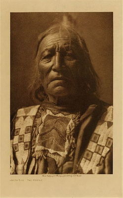 Edward S. Curtis -   Short Log - Two Kettle - Sioux - Vintage Photogravure - Volume, 12.5 x 9.5 inches - From Edward S. Curtis' "The North American Indian," Volume III, this image portrays a Sioux man named Short Log - Two Kettle. Pictured here in an elaborately decorated shirt, likely made of skin.<br><br>This photogravure was taken in 1907 by Edward S. Curtis. The piece was printed on Japon Vellum and is available for sale in out Aspen Art Gallery.<br><br>Provenance: <br>Art Institute of Chicago, Ryerson & Burnham Library