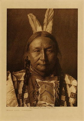 Edward S. Curtis -   Yellow Hawk - Yanktonai - Vintage Photogravure - Volume, 12.5 x 9.5 inches - Born in 1854 near Fort Berthold, North Dakota. When he was sixteen he accompanied a war-party, but achieved nothing. While in an engagement with the Apsaroke near Musselshell river, Montana, he rushed into the thick of the fight and brought out his brother's dead body. Somewhat older, he was leading a war-party when a single Indian was seen. Wishing to fight him single-handedly, Yellow Hawk commanded his warriors to wait; he then charged the stranger, killing him with his war club. On another expedition he killed one enemy and counted a first coup. He captured a tethered horse from the Atsina near Fort Belknap, and another from the Cree. Yellow Hawk fasted many times and always had the same vision- that an old man in the clouds with his body painted blue and his legs read. This old man told him he would never be wounded, but would gain many honors and live to great age. Yellow Hawk married at twenty-three.<br><br>Provenance: <br>Art Institute of Chicago, Ryerson & Burnham Library